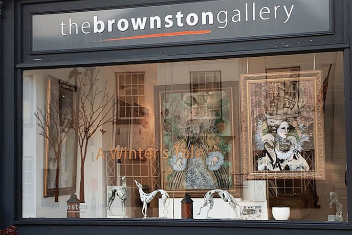 The modern exterior of The Brownston Art Gallery, with a window full of beautiful contemporary art