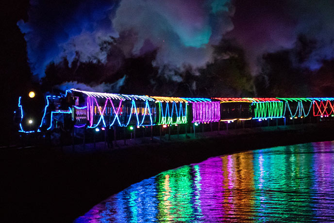  The Christmas Train of Lights going round a lake with all the lights reflected in the water