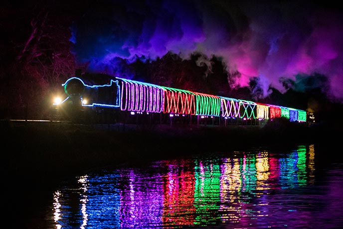  The Christmas Train of Lights going round a lake with all the lights reflected in the water