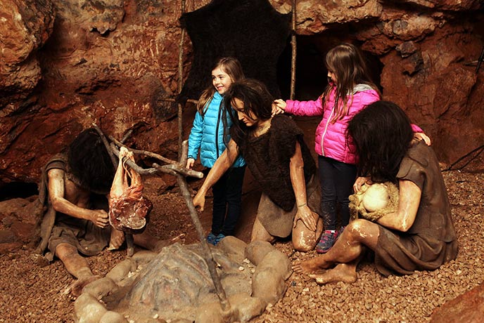 Two children in amongst the caveman statues at Kents Cavern