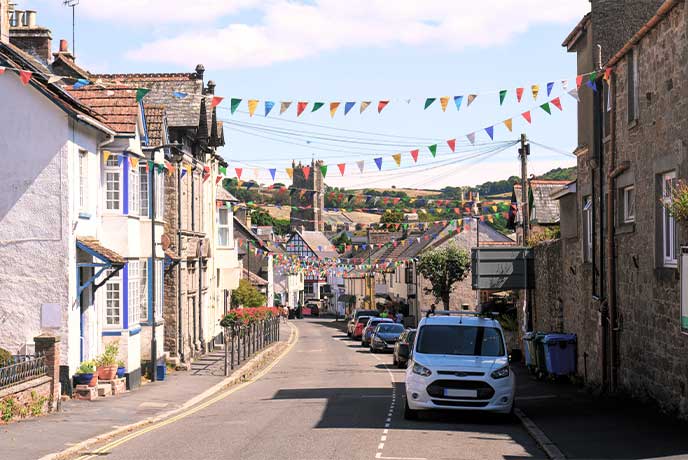 Pretty stone houses down a street in Moretonhampstead in Dartmoor National Park with bunting hanging between the houses and a church in the distance
