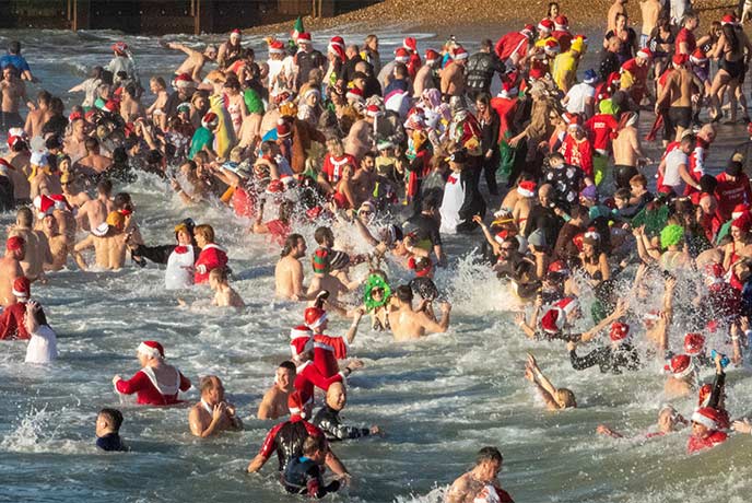 People in Santa hats running into the sea in Bournemouth as part of the Macmillan White Christmas Dip