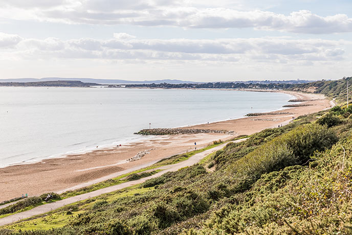 The long stretch of sand at Highcliffe beach in Dorset with groynes separating the different sections of the beach including the dog-friendly patch
