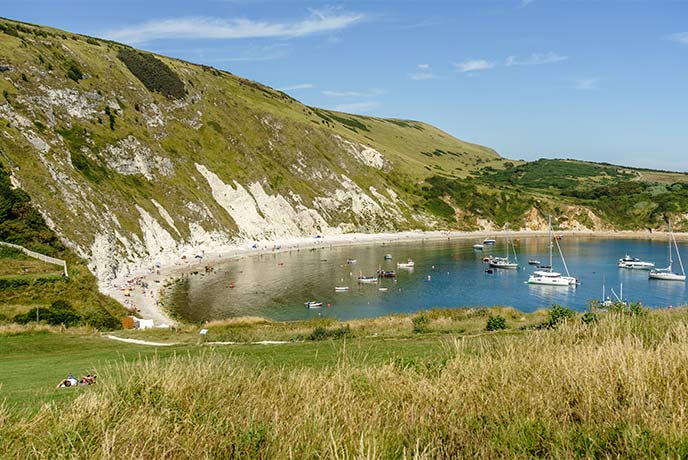 The iconic circular Lulworth Cove with boats floating in the water