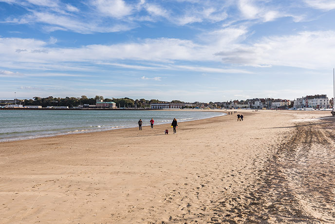 People walking along the golden sands at Weymouth beach