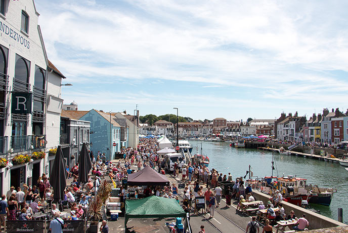 People walking along the stalls and harbour at Weymouth Food Festival