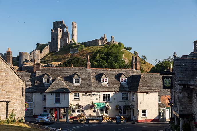 Looking over a pub and houses at the ruins of Corfe Castle on the hill above