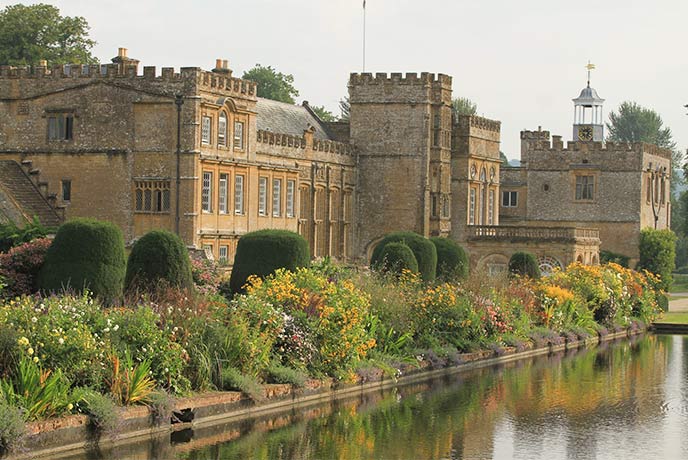 The historic building of Forde Abbey Gardens in Dorset alongside flower beds and a lake