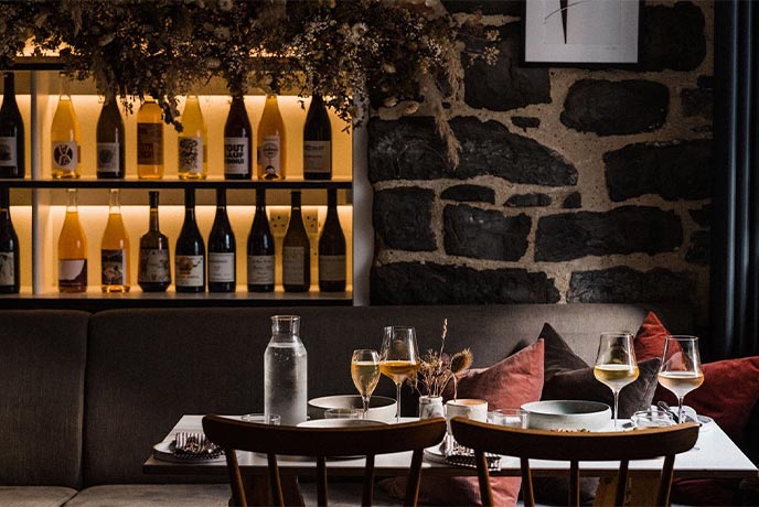 A cosy dining room with stone walls and lit wine shelf at Lilac in Lyme Regis