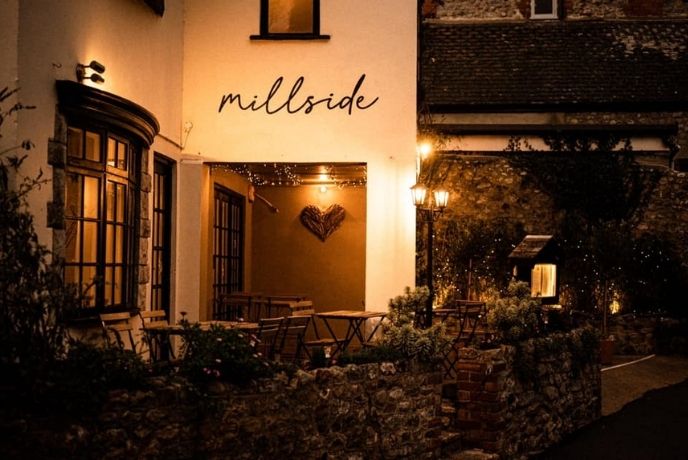 The exterior of Millside at night with fairy lights covering the surrounding bushes