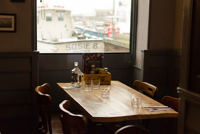 A cosy dining room table overlooking the harbour at The Cobb Arms in Lyme Regis