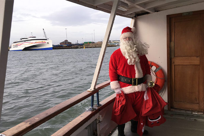 Santa standing on a boat in Poole Harbour in Dorset
