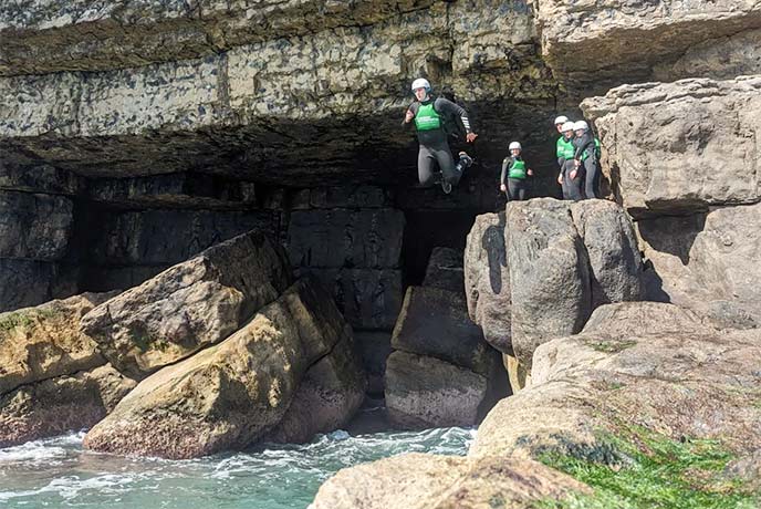 People coasteering and jumping into the sea with Jurassic Watersports along the Dorset coast