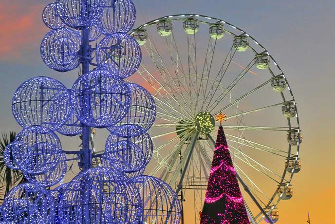 A towering Christmas tree made of circular lights with an illuminated ferris wheel in the background at Christmas in Bournemouth