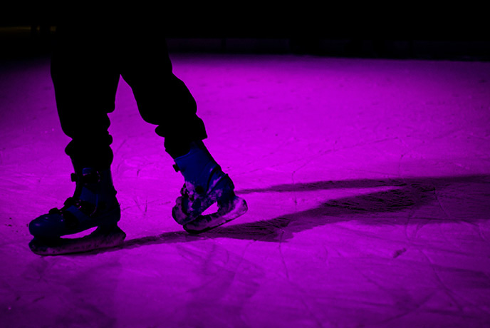 Someone ice skating in the dark under a purple light