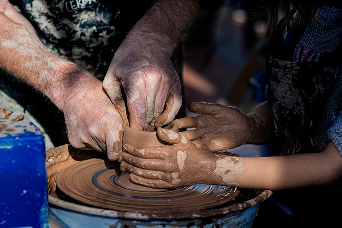 Two people making a pot on a pottery wheel