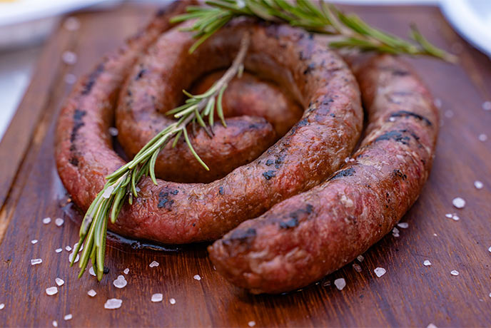 A cooked Cumberland sausage garnished with thyme