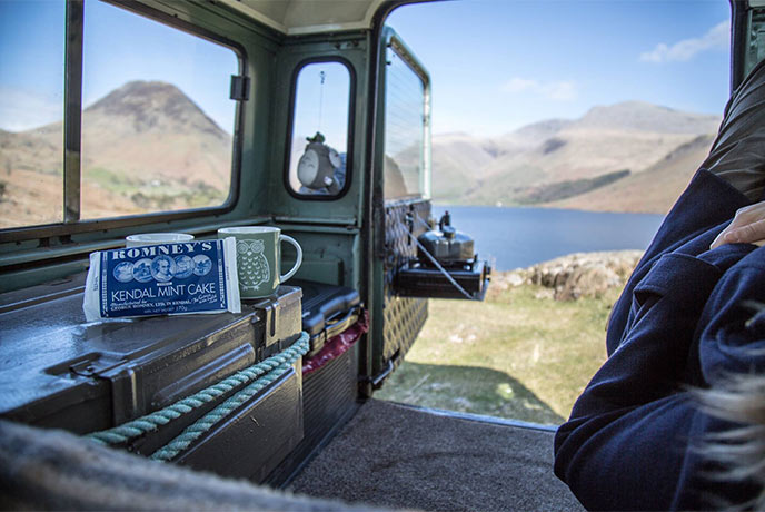 A jeep sat above the fells and lakes in the Lake District with a Kendal Mint Cake on the dashboard