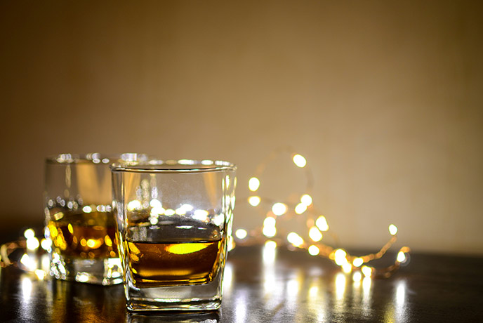 Two glasses of whisky with some fairylights behind