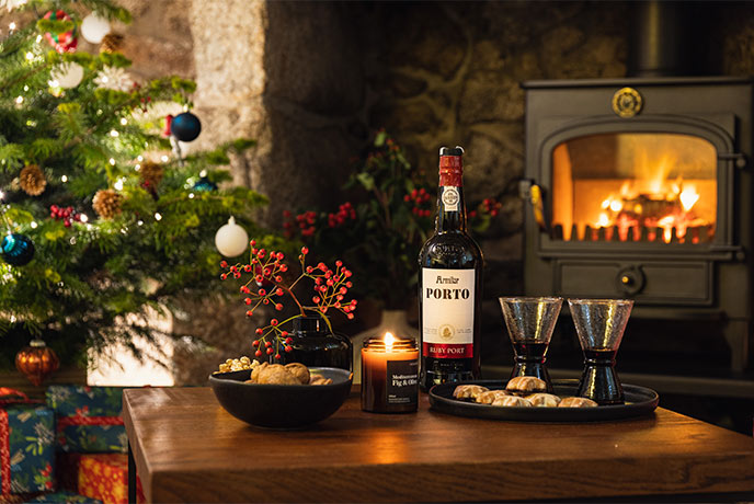 A selection of festive foods and port in front of a fireplace and Christmas tree