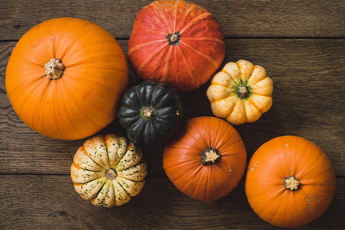 A selection of pumpkins of different colours and sizes on a wooden table