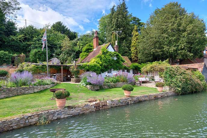 The fairytale setting at Myrtle Cottage, with a colourful garden next to a flowing river
