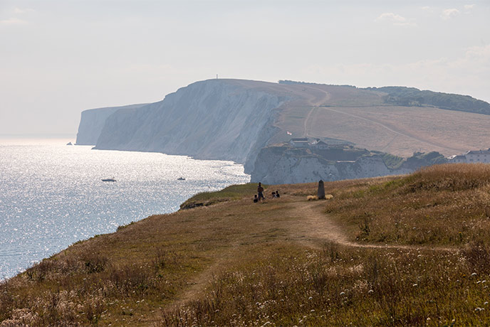 People walking along the cliffs above Freshwater with The New Battery in the distance