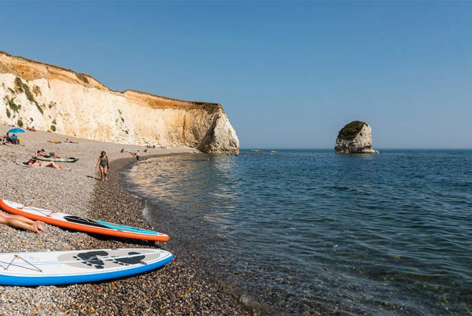Paddleboards resting on the beach by the water at Freshwater Bay on the Isle of Wight