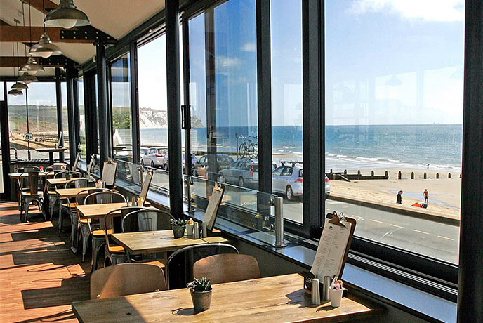 Looking out over the tables and out of the window at the sea at The Bandstand