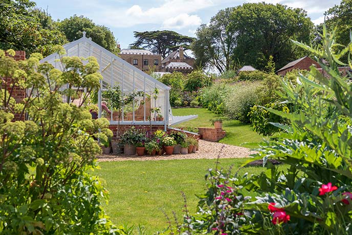 A pretty greenhouse surrounded by flowers in the grounds of Farringford House on the Isle of Wight