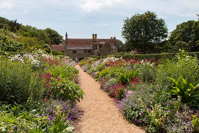 Looking down a pretty garden path with stunning floral borders at Mottistone Gardens and Estate