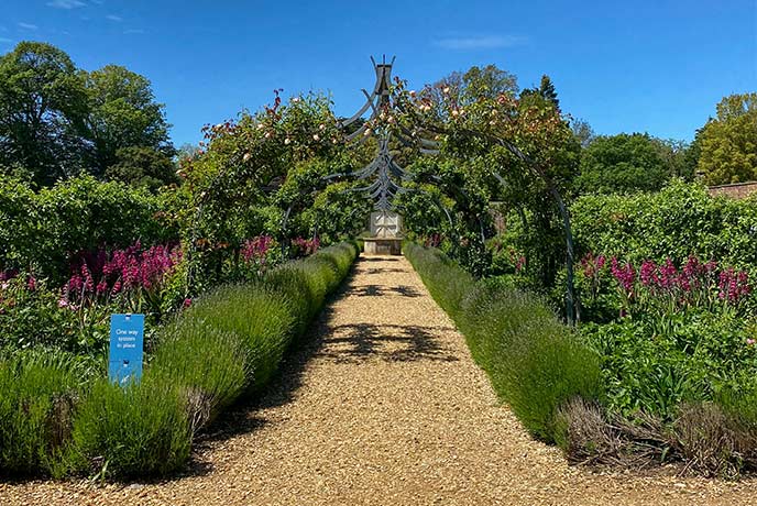 Looking down a pretty garden path surrounded by colourful borders in the gardens of Osborne House