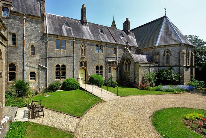A pretty gravelled courtyard with floral borders in front of the historic Carisbrooke Priory