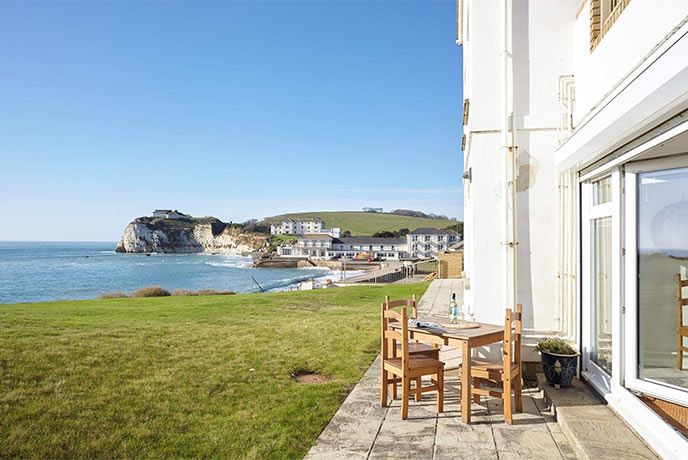 An outside table in front of a holiday cottage on a cliff with amazing sea views in the background