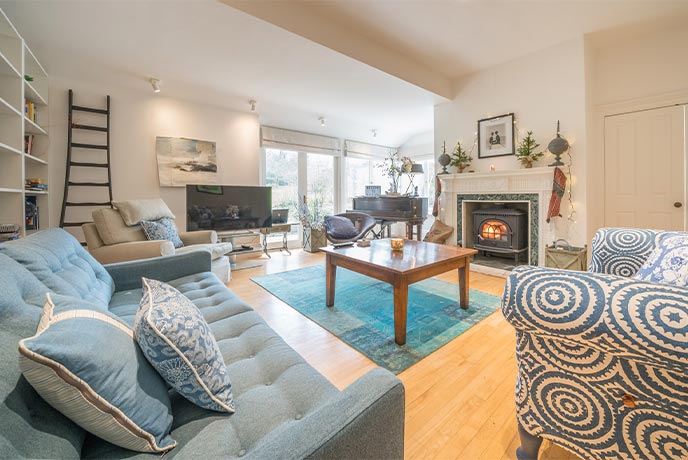 The spacious coastal themed living room at Bayside House on the Isle of Wight with a lit wood-burner