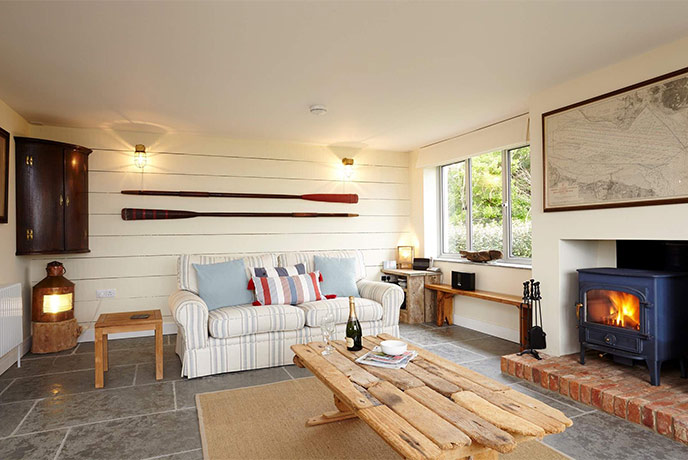The cosy living room with paddles on the wall and a wood-burner at Flackstead