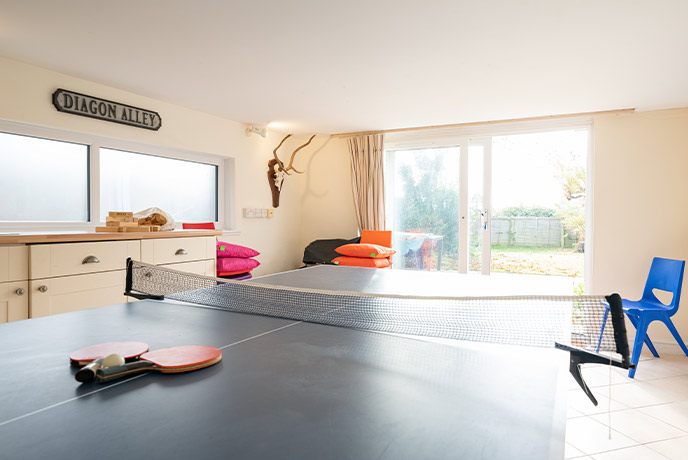 A table tennis table in a games room with the garden in the background