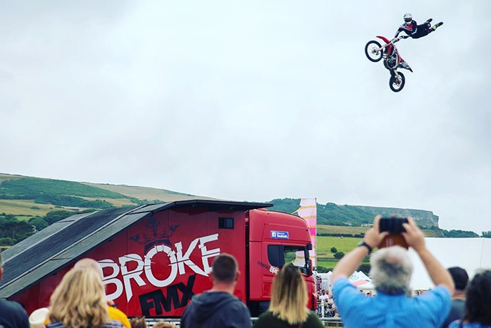 A stunt performer up in the air with their motorcycle at Chale Show