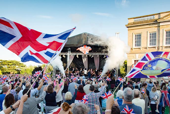 An energetic crowd in front of the stage at Wight Proms waving flags