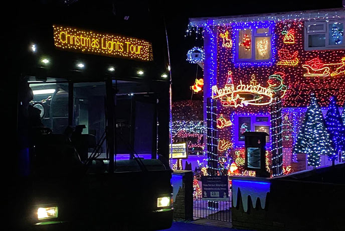 The fun-filled Christmas Lights Tour bus and a dazzling Christmas lights display behind