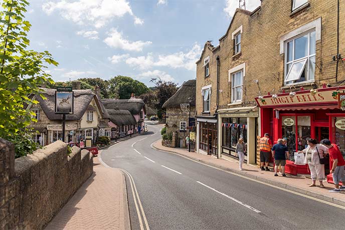 Looking down a street in Shanklin Old Village with thatched cottages along the road and a Christmas shop with a red storefront