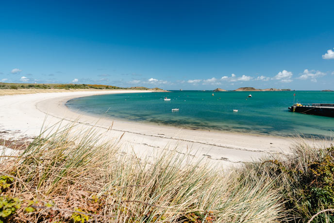 A curve of white sand and turquoise waters at St Martins Beach on the Isles of Scilly