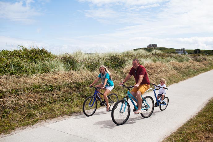 A family cycling down a country lane on the Isles of Scilly