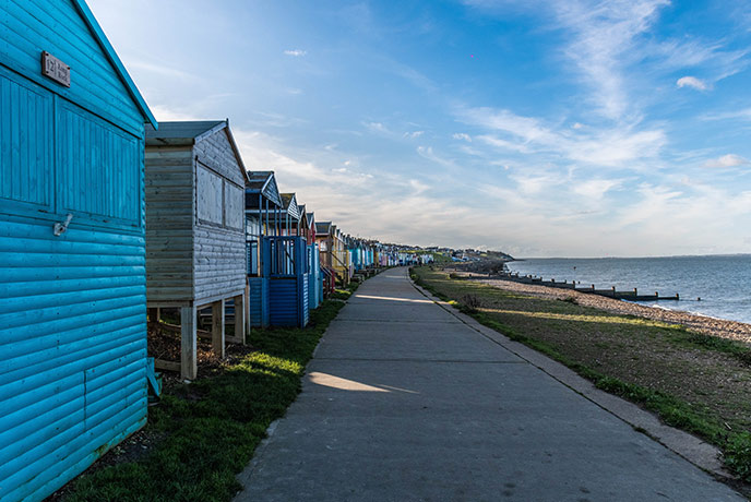 A line of colourful beach huts look over Whitstable beach in Kent