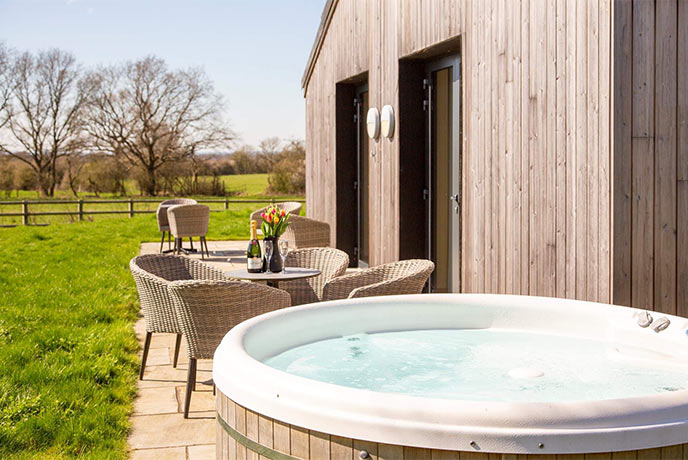 The pretty hot tub and outside dining table at Stags Barn in Kent