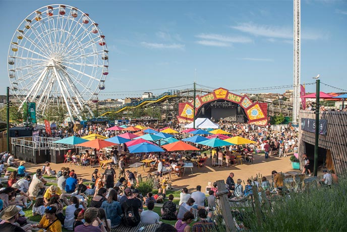 Crowds of people at Dreamland Margate with a giant Ferris wheel in the background