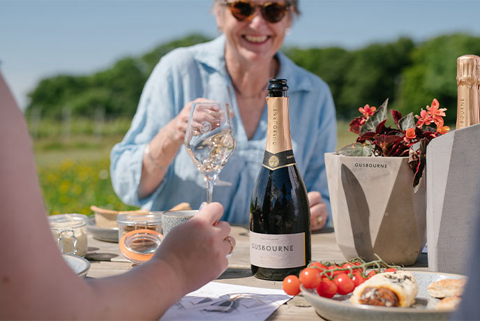 People enjoying a picnic with wine at Gusbourne vineyard in Kent