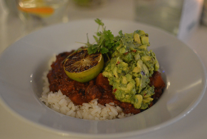 Muddy Beach vegan chilli is perfectly presented in pristine white dishes and garnished with a grilled lime, leaves and guacamole for flavour.