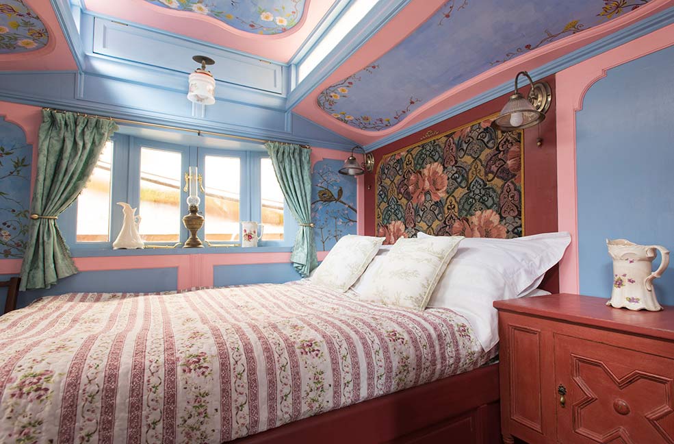 The bedroom is filled with beautiful details including the hand-painted wood panels that brighten up this space with pastel colours and floral patterns.