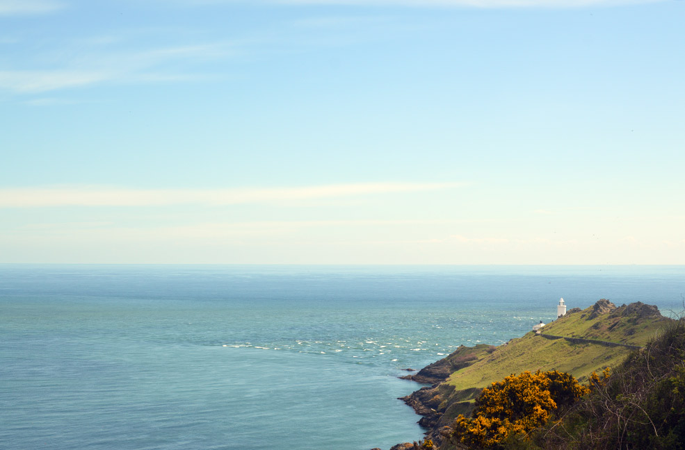 A far away view of Start Point Lighthouse overlooking the beautiful blue sea of Start Bay in South Devon.